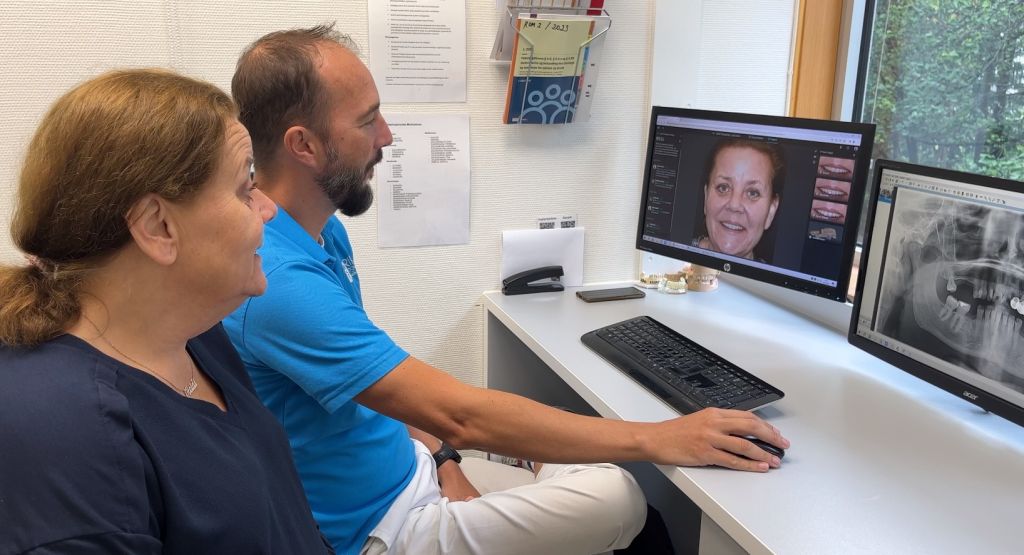 Tannlege Adrian Matic viser en pasient det planlagte resultatet på skjerm med smiledesign hos OralCare